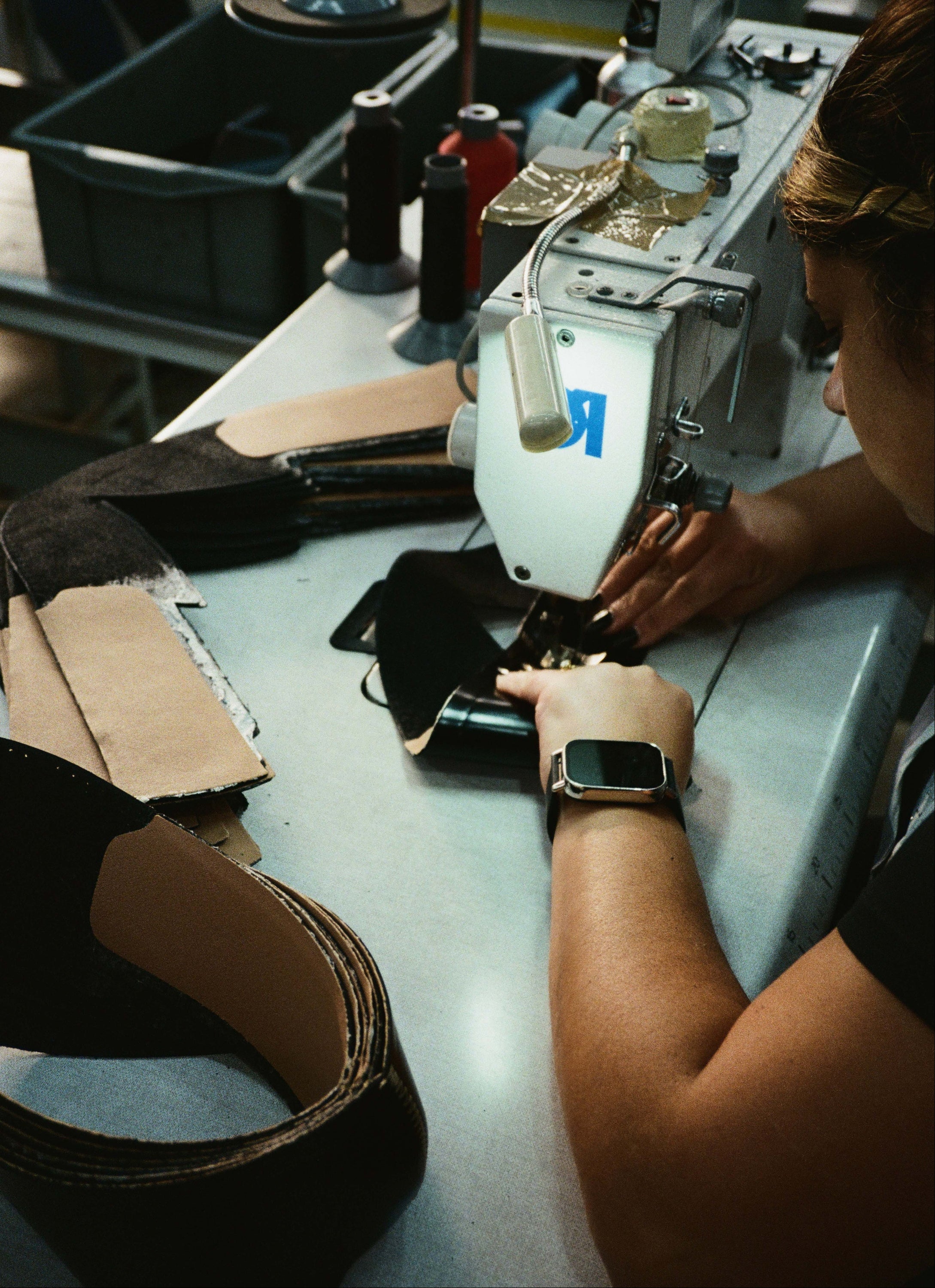 Person working on a sewing machine with leather pieces in a workshop setting